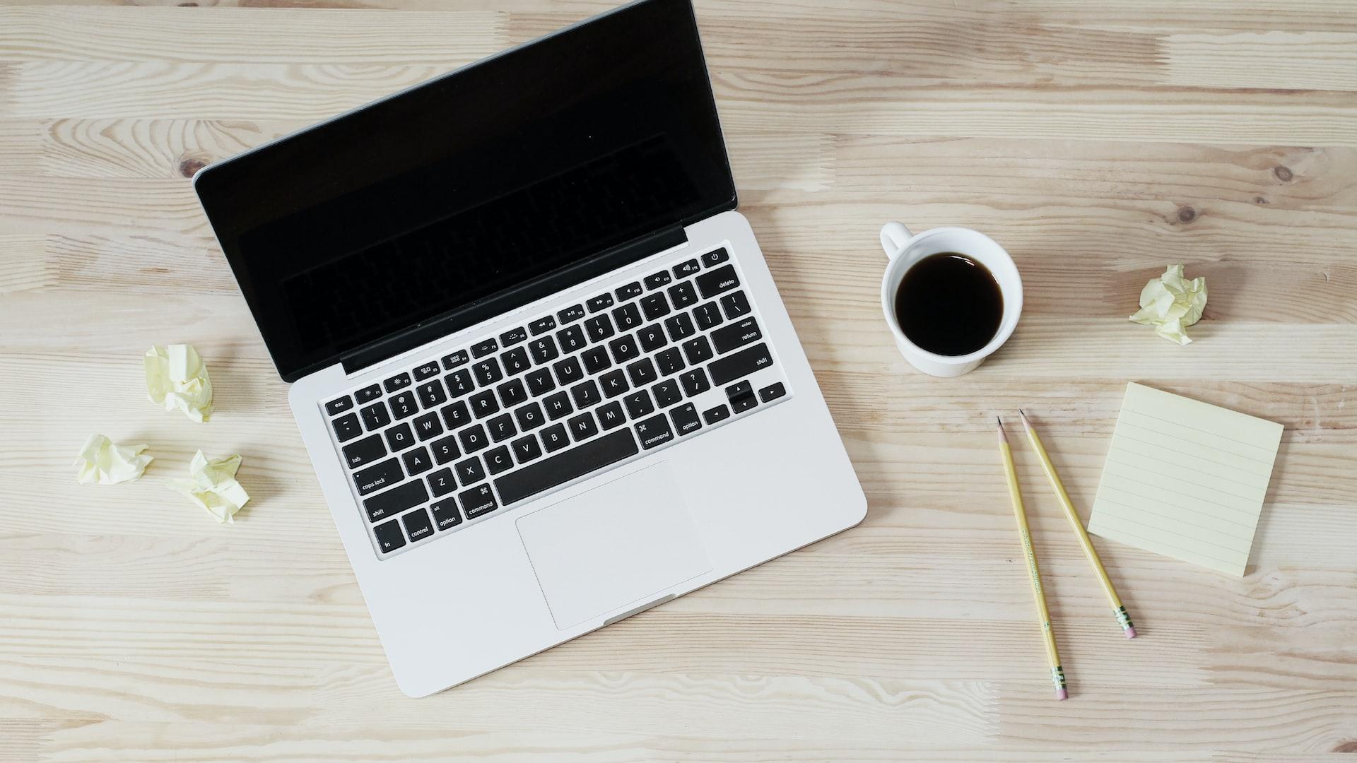turned off MacBook Pro beside white ceramic mug filled with coffee